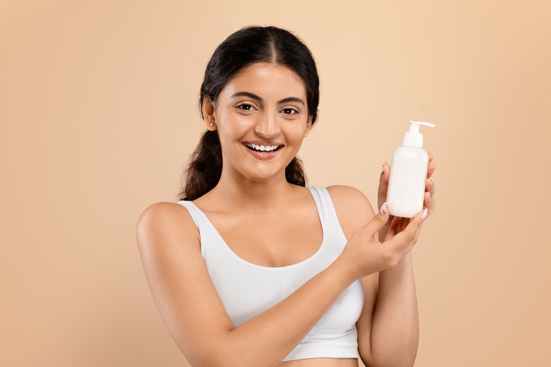 Indian woman with beautiful smile holding white lotion dispenser