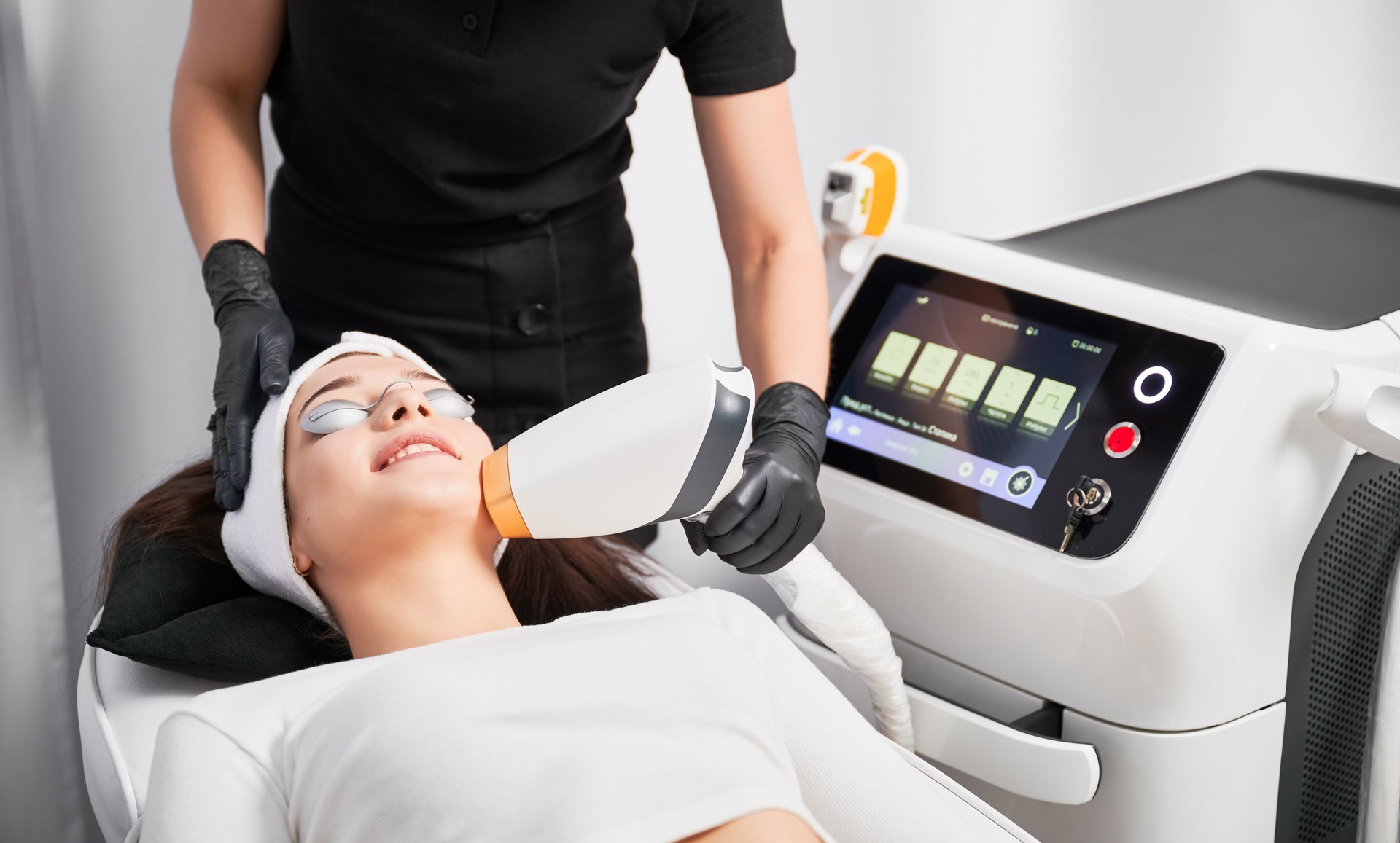 Woman receiving laser facial treatment in cosmetology clinic.