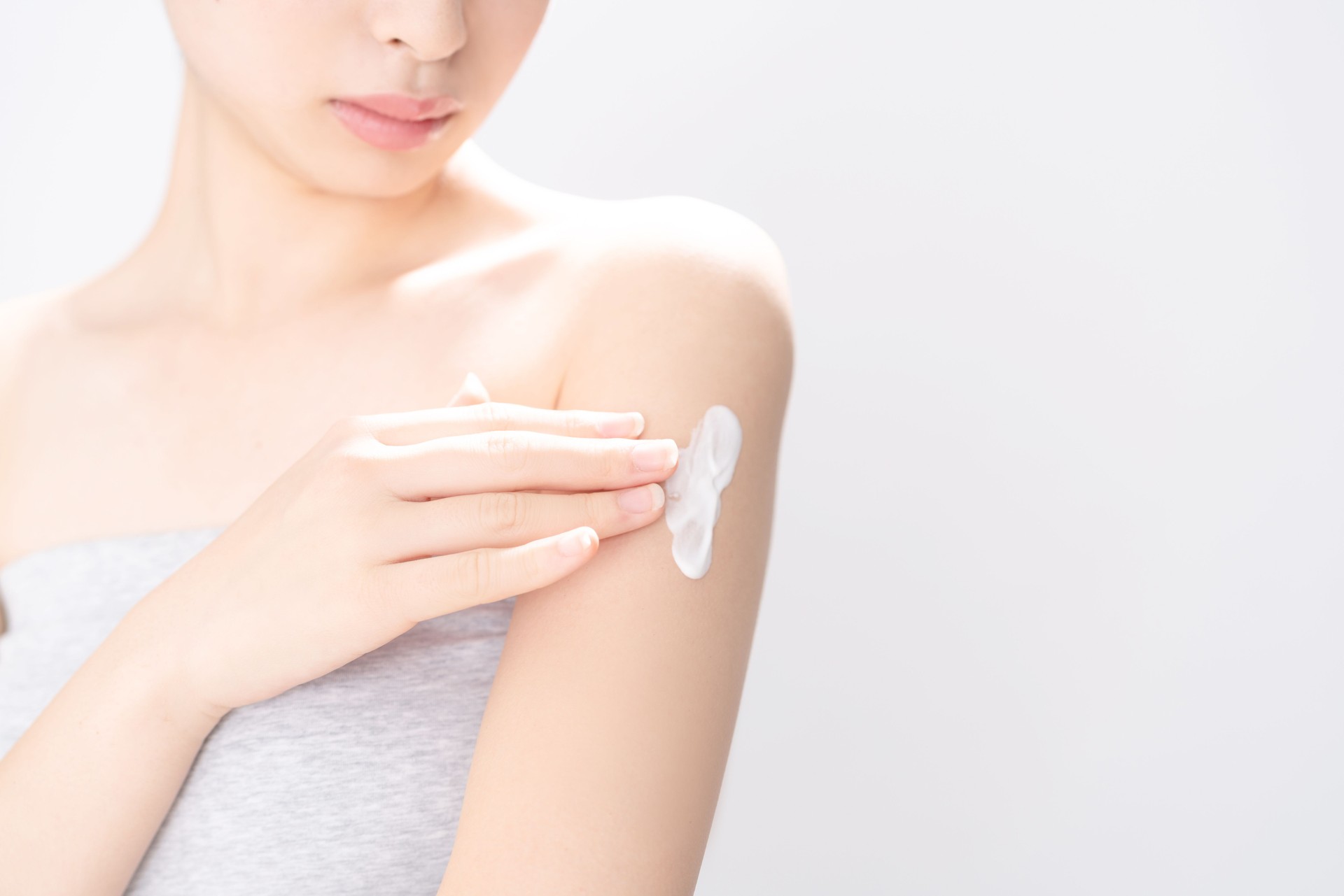 Young woman applying cream on her arm.