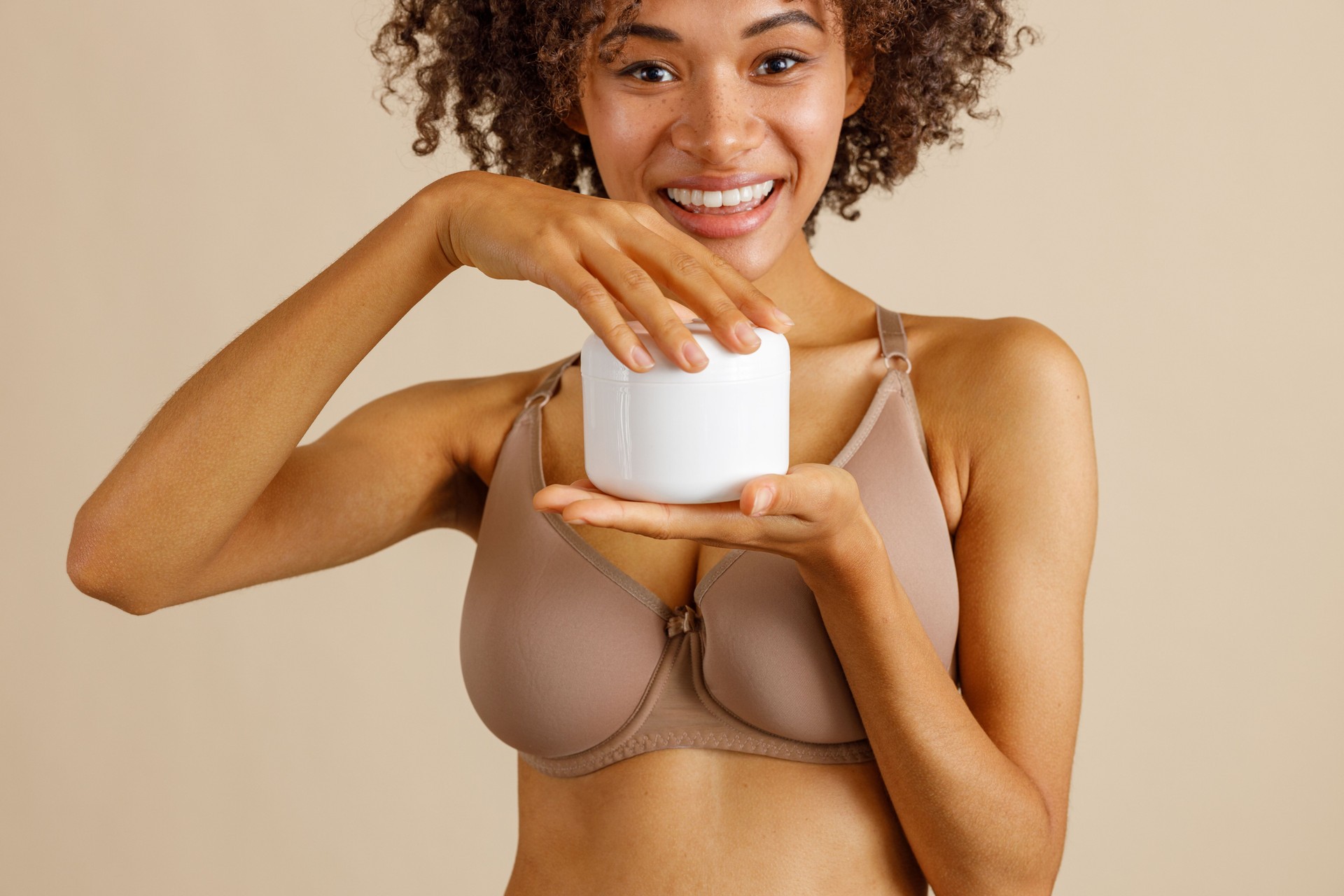 Young woman holding bottle with beauty product in studio