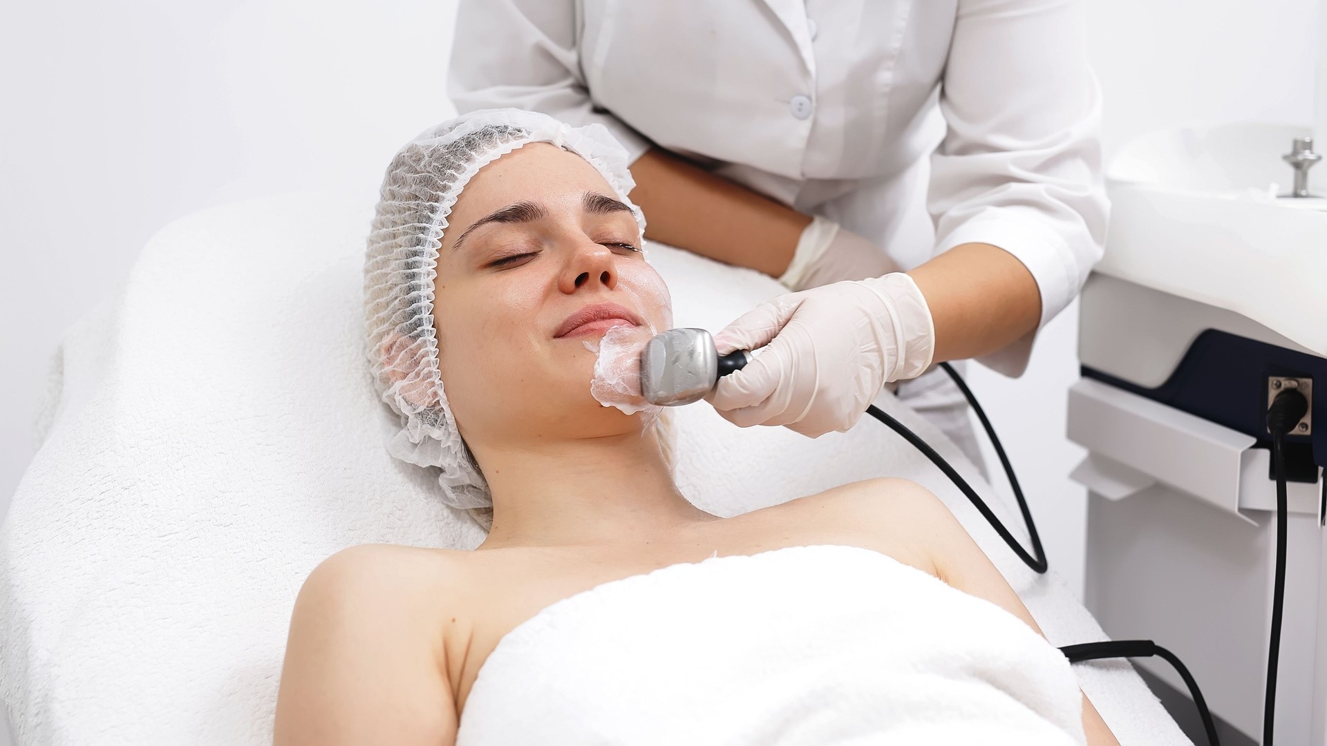 A cosmetologist applies radiofrequency lifting to a young woman in a modern clinic. This advanced procedure tightens skin and promotes rejuvenation, ideal for showcasing beauty treatments.