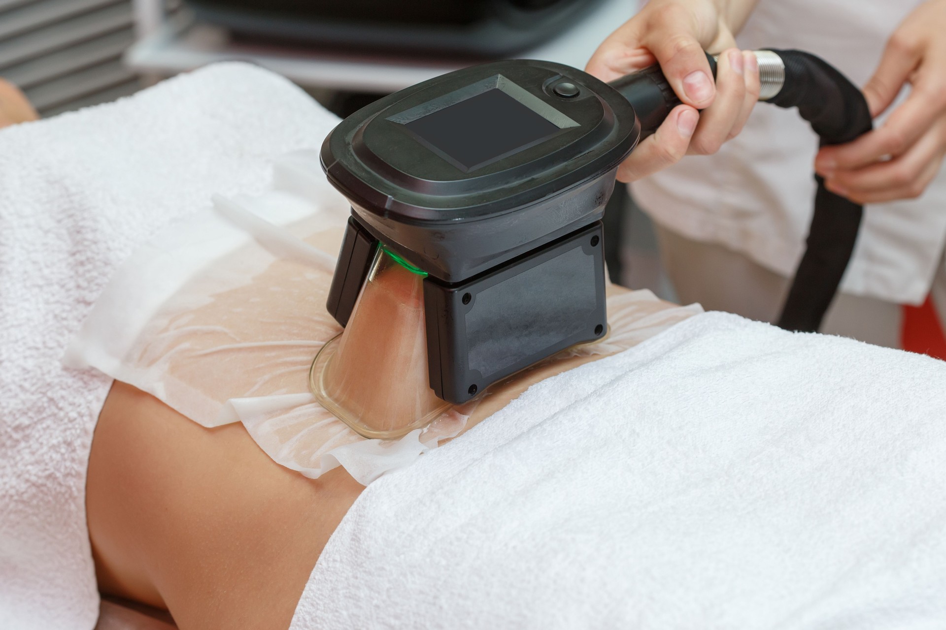 Woman getting cryolipolysis fat treatment in professional cosmetic cabinet